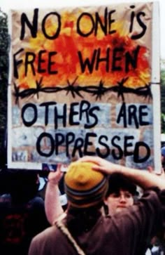 a man holding up a sign that says no one is free when others are oppressed