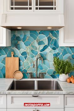 a kitchen sink under a window with blue tiles on the backsplash and white cabinets