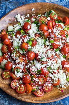 a wooden bowl filled with lots of tomatoes and cheese