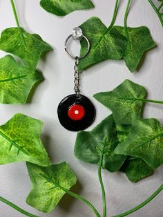 a black and red keychain sitting on top of green leafy plant life