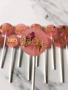 pink lollipops with gold letters on them sitting on top of each other