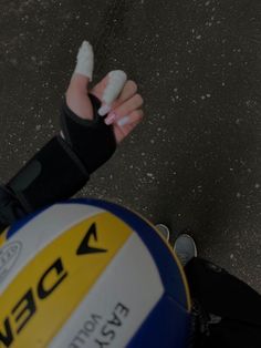 a person with bandages on their arm holding a white and blue ball in the street