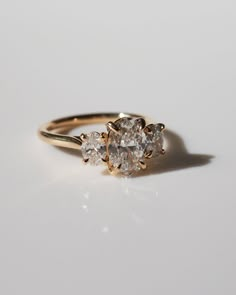 a three stone diamond ring on a white surface