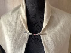 a close up of a person wearing a white jacket and tie with a silver bar on it