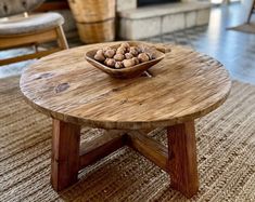 a wooden table with a bowl of nuts on it in a living room next to a chair