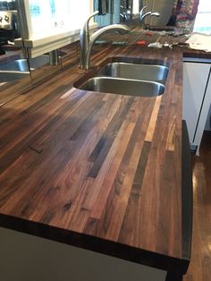 a wooden counter top in a kitchen with stainless steel sink and faucet above it