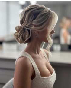 a woman with blonde hair in a low bun hairstyle looking off to the side