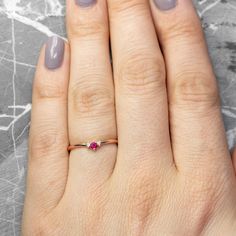 a woman's hand with a ring on it and a pink stone in the middle