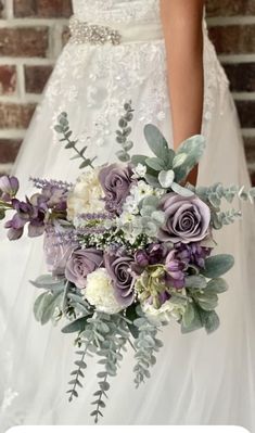 a bridal holding a bouquet of flowers in front of a brick wall