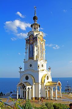 a tall white church tower sitting next to the ocean