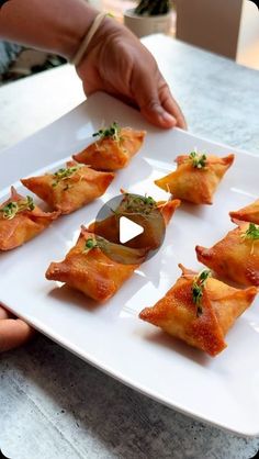 a white plate topped with food on top of a table next to a person's hand