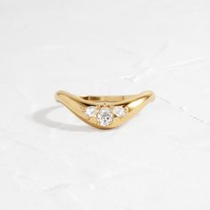 a gold ring with three diamonds on it, sitting on top of a white surface