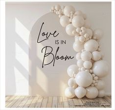 a balloon arch with the words love is in bloom written on it and white balloons