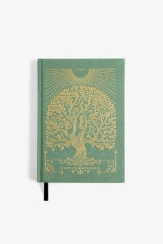 a green and gold book with an image of a tree on the cover, in front of