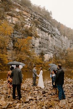 a group of people standing on top of a river holding umbrellas