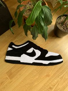 a black and white rug on the floor next to a potted plant with green leaves