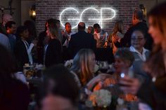 a group of people sitting at tables in front of a brick wall with the word go written on it