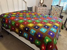 a crocheted blanket is on top of a bed in a room with white walls