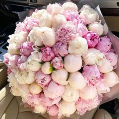 a bouquet of pink and white peonies in the back seat of a car