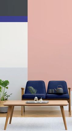 two blue chairs sitting next to each other in front of a pink and white wall