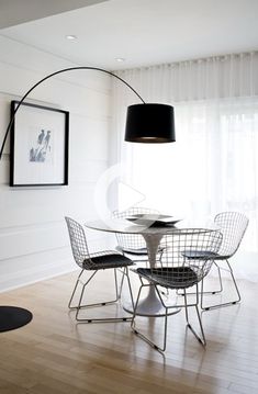 a dining table with four chairs and a black lamp in the middle of the room