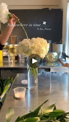 a woman arranging flowers in a vase on a counter top with the words somewhere in time written above it