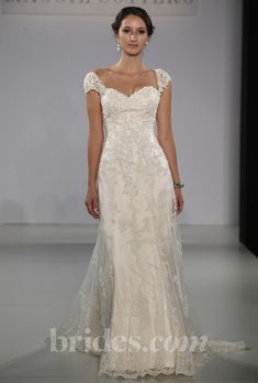 a woman is walking down the runway wearing a wedding dress with an open back and short sleeves