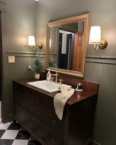 a bathroom with a sink, mirror and checkered flooring on the floor in front of it