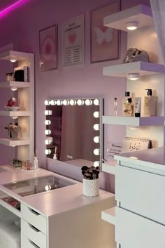 a white vanity with lights on it in a room that has pink walls and shelving