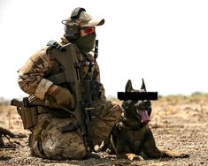 a man in camouflage sitting next to a dog