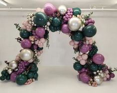 an arch made out of balloons and greenery in the shape of a letter o