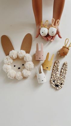 a child's hand is holding some paper bunny and other animal decorations on the table