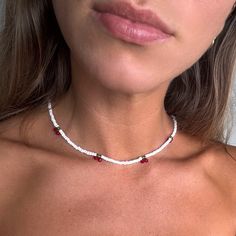 a woman wearing a red and white beaded choker necklace on her neck, looking at the camera