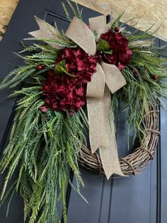 a wreath with red flowers and greenery tied to it