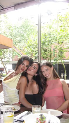 three women are posing for the camera at a restaurant