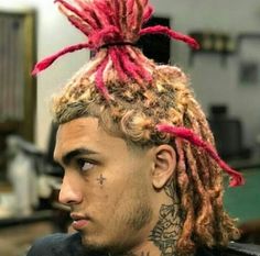 a man with red dreadlocks sitting in a barbershop wearing a black t - shirt