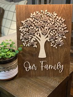 a wooden sign with the words our family on it next to a potted plant