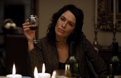 a woman sitting at a table holding a wine glass in front of her with candles on the table