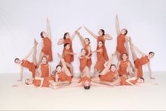 a group of women in orange dresses are posing for a photo with their arms and legs up