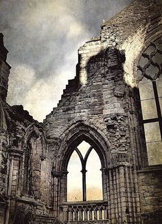 an old stone building with a window and stairs leading up to the top floor, in front of a cloudy sky