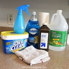 various cleaning products sitting on top of a counter next to a bottle of detergent