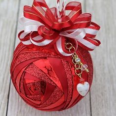 a red christmas ornament with white and gold decorations on the top, sitting on a wooden surface