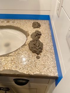 a white sink sitting on top of a counter next to a blue and white cabinet