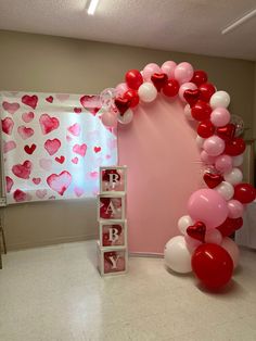 the balloon arch is decorated with red, white and pink balloons for a baby's first birthday