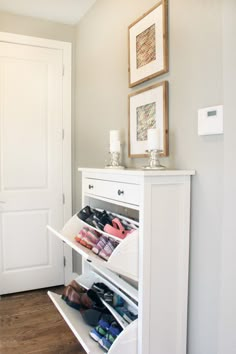 a white shoe rack in the corner of a room next to a door with pictures on it