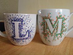 two coffee mugs sitting on top of a wooden table covered in confetti