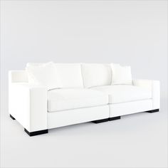 a white couch sitting on top of a white floor next to a gray wall with black legs