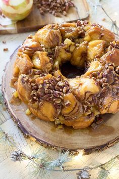 an apple cinnamon bundt cake on a wooden platter with pine cones around it