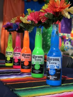 six bottles of corona extra are lined up on a table with flowers in the background