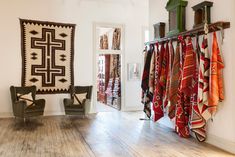 a room filled with lots of different types of fabrics hanging on the wall and two green chairs